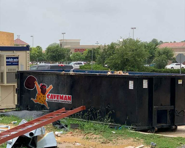 caveman roll off dumpster at work site